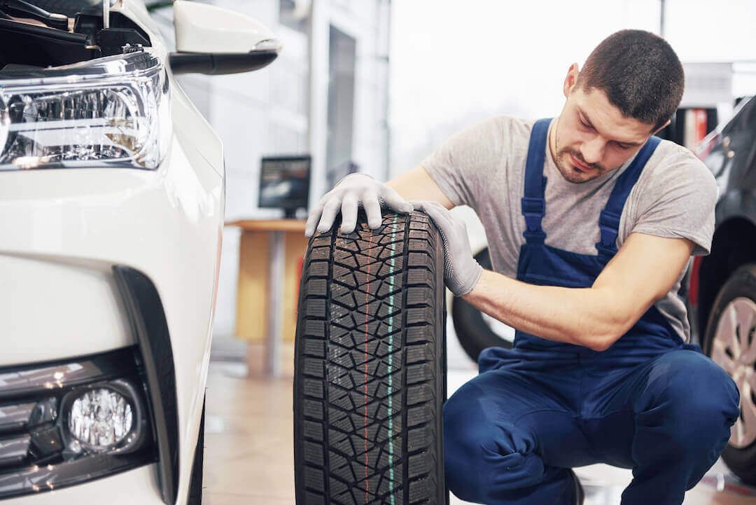 Mécanicien tenant un pneu et observant la technologie de celui-ci dans un garage automobile