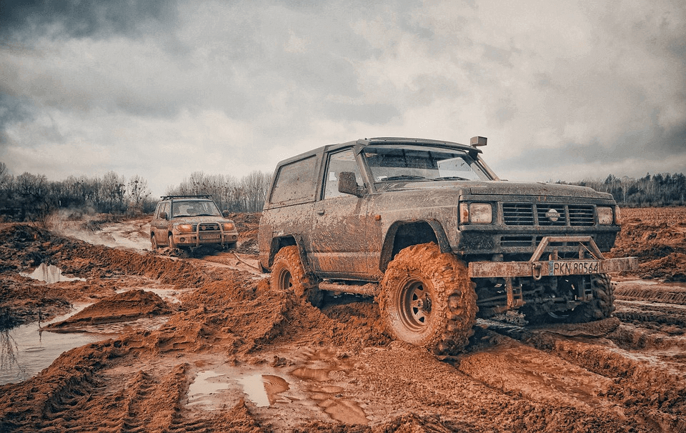 two 4x4 in a mud covered off-road track