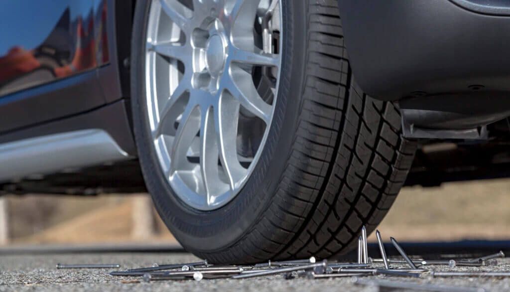 Close-up of a Bridgestone Runflat tire rolling over a pile of nails