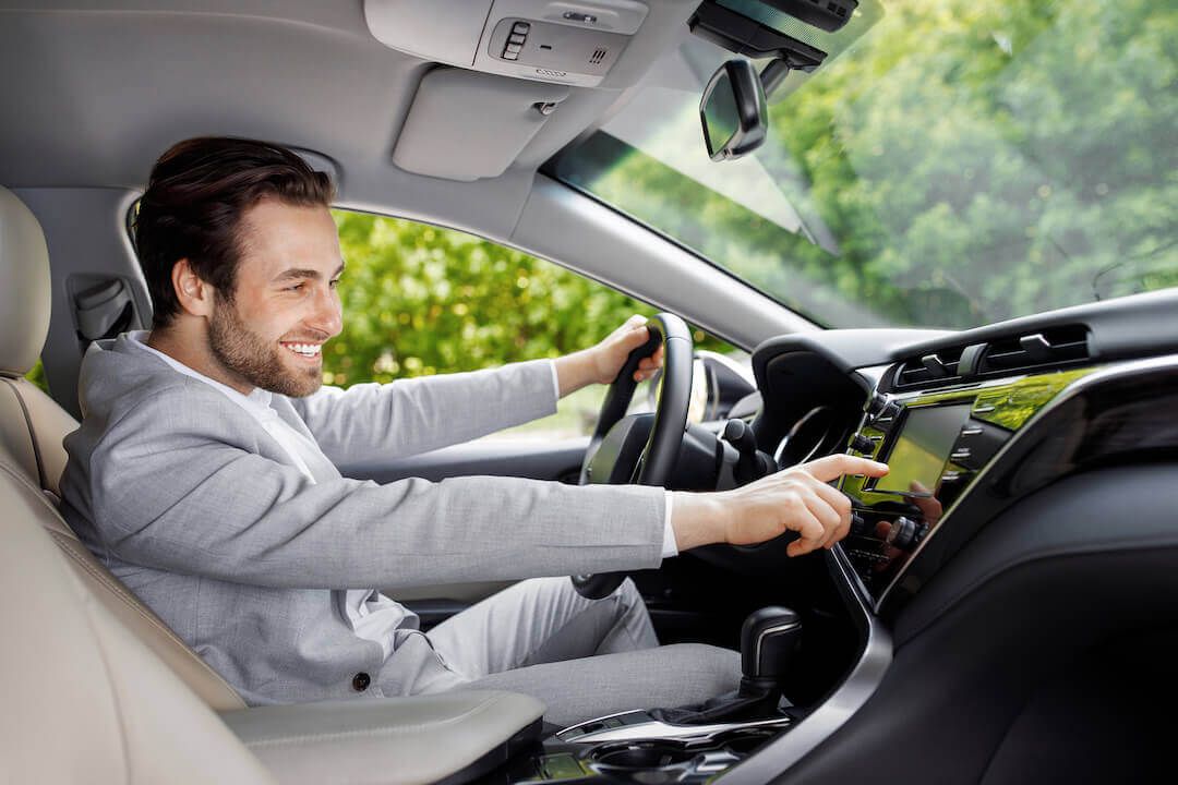 Comfortable man driving his car experimenting with the on-board screen technology