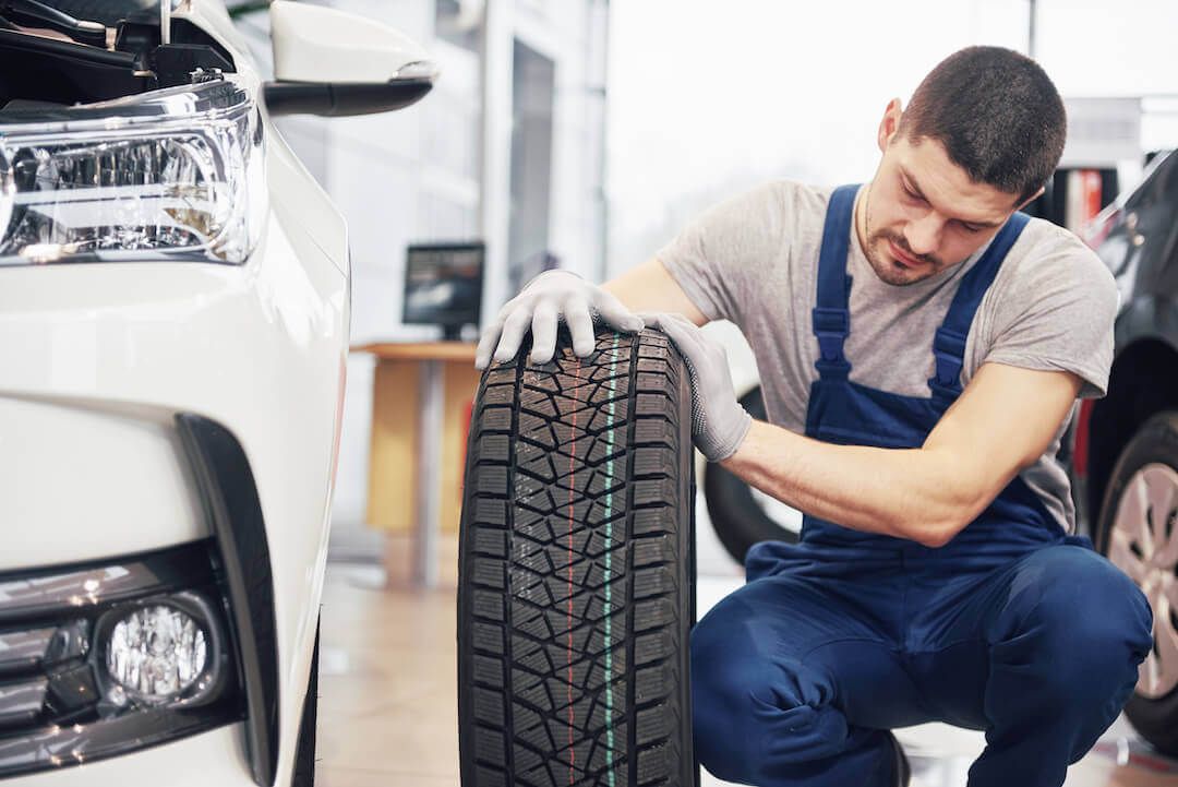 Mechanic holding a tire and observing the technology of it in a car garage