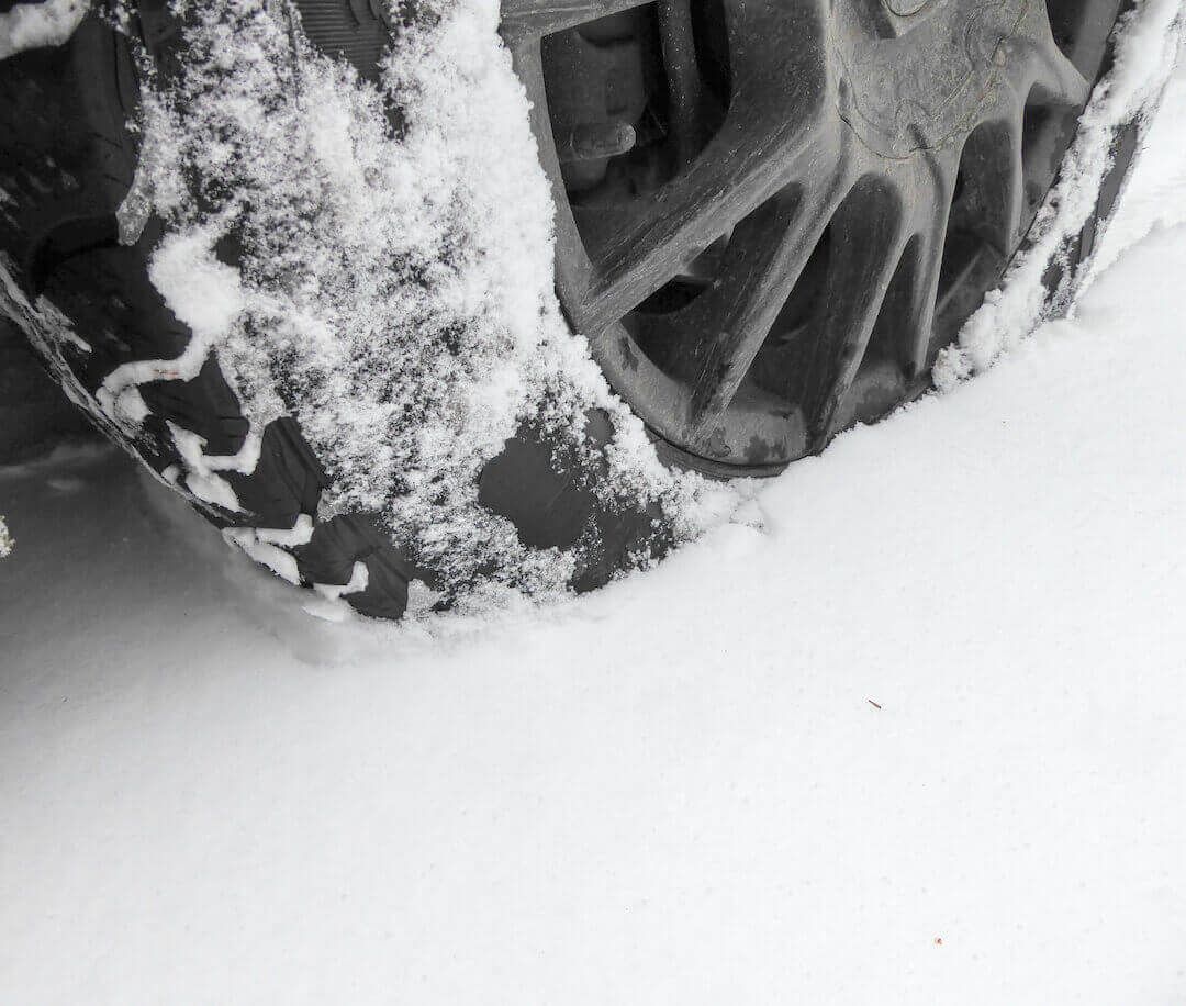 Close-up of an all-terrain tire compacting the snow ahead of it