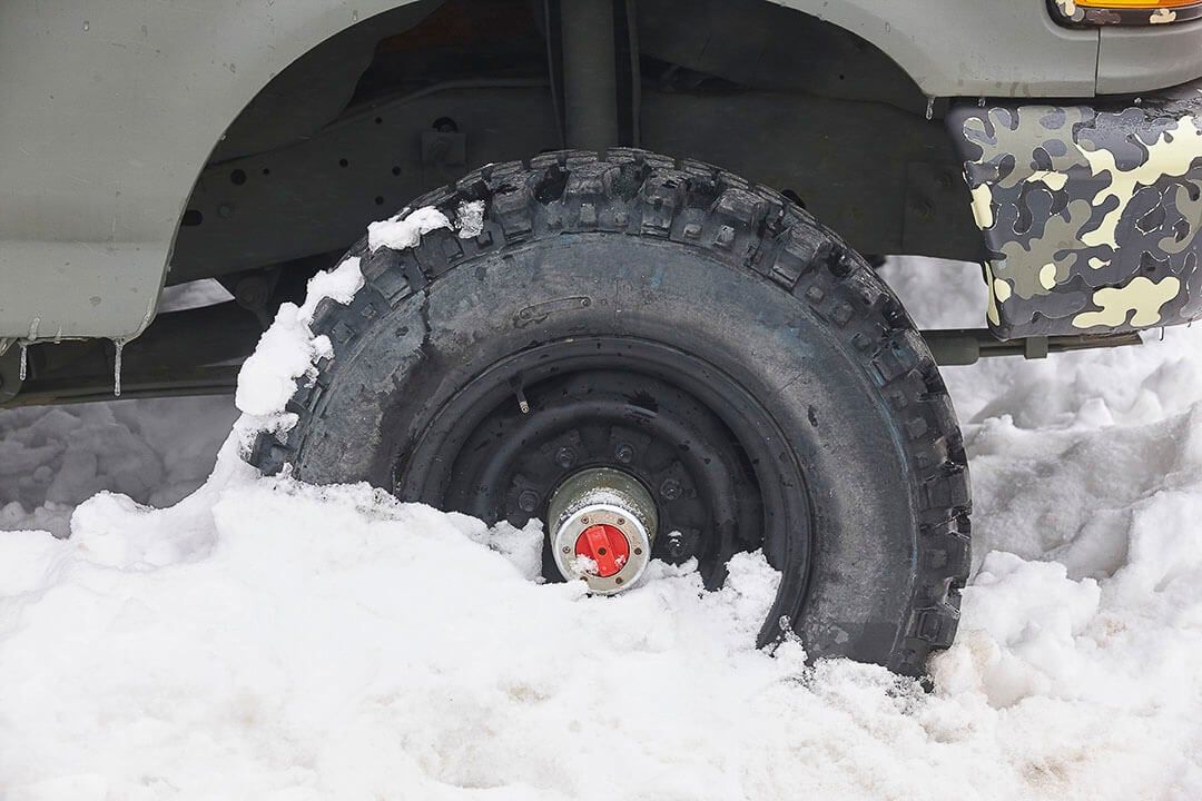 side view of a winter tire bpartially buried in snow